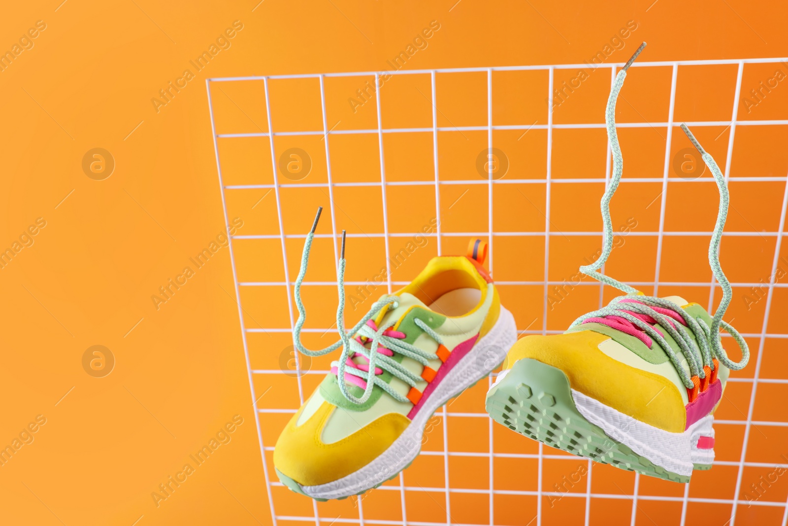 Photo of Stylish presentation of trendy sneakers on orange background. Space for text