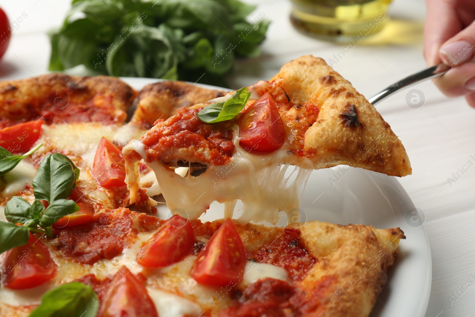 Photo of Woman taking piece of delicious Margherita pizza at white table, closeup