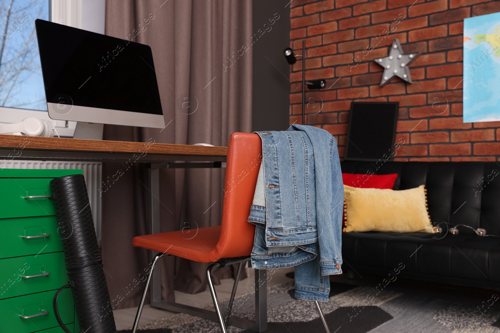 Photo of Stylish teenager's room with computer and black sofa near brick wall