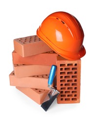 Photo of Many red bricks, hard hat and trowel on white background
