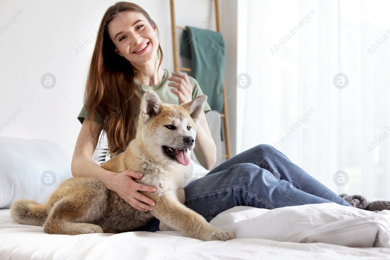 Photo of Young woman with adorable Akita Inu dog in bedroom