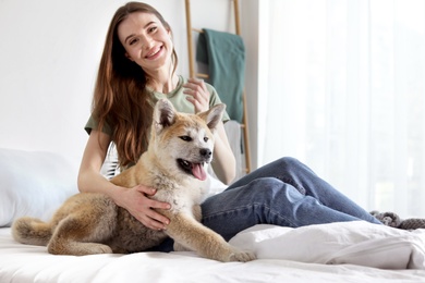 Young woman with adorable Akita Inu dog in bedroom