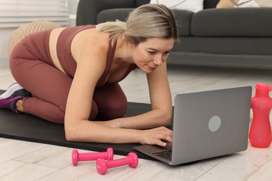 Photo of Online fitness trainer. Woman watching tutorial on laptop at home