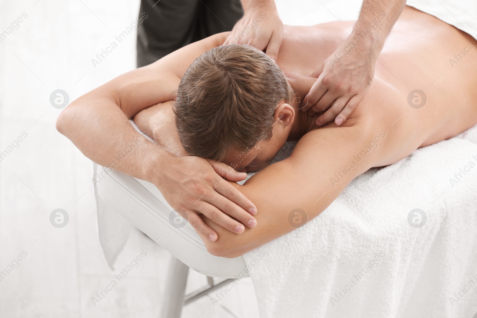 Photo of Relaxed man receiving back massage in wellness center