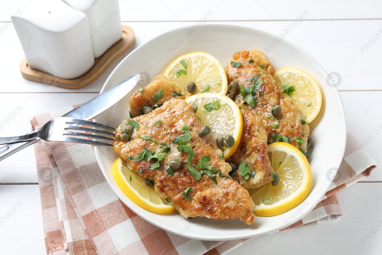 Photo of Delicious chicken piccata served on white wooden table