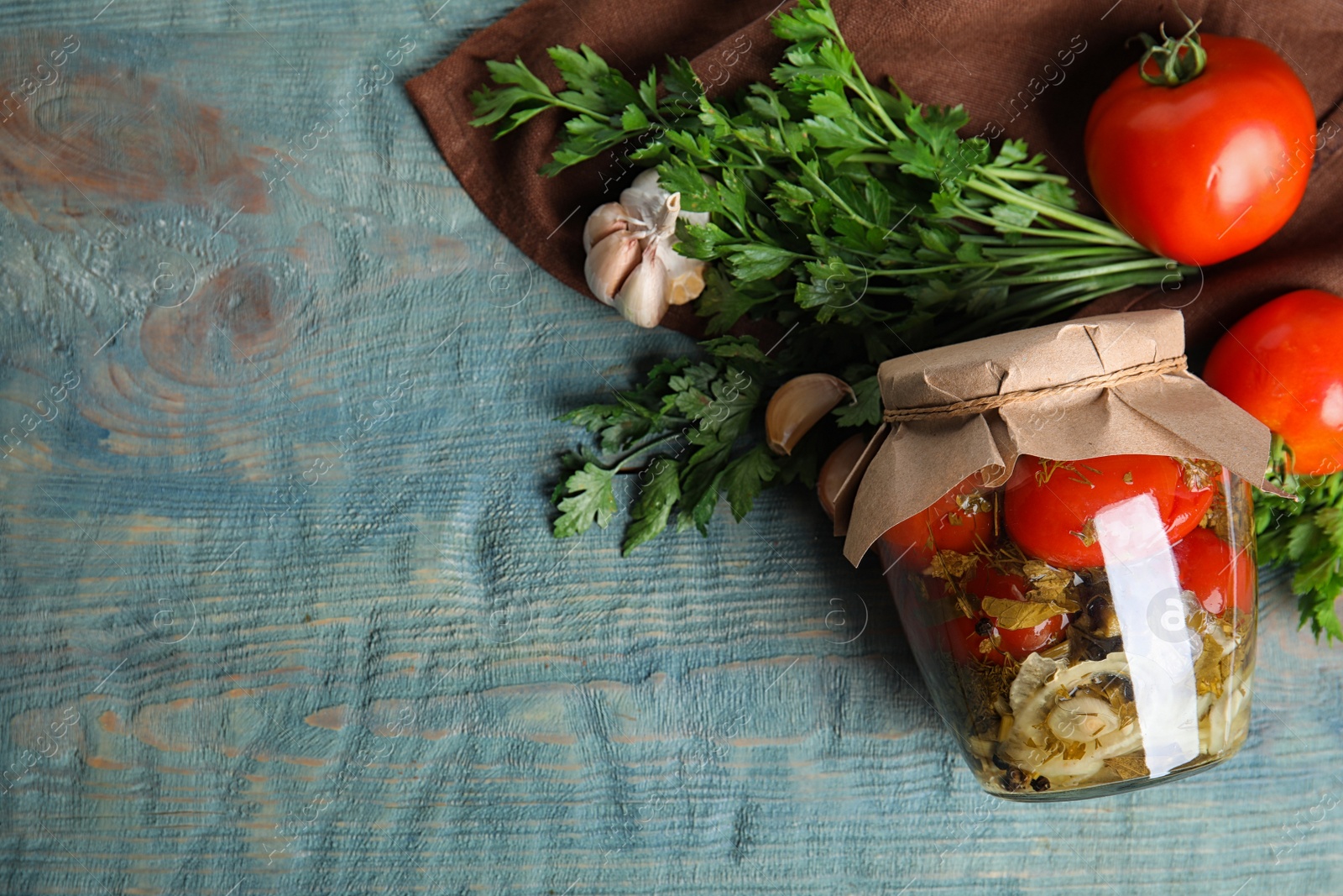 Photo of Flat lay composition with pickled tomatoes in glass jar on blue wooden table, space for text