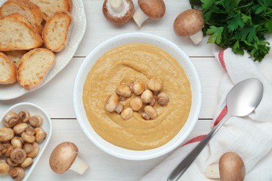 Photo of Delicious mushroom cream soup served on white wooden table, flat lay