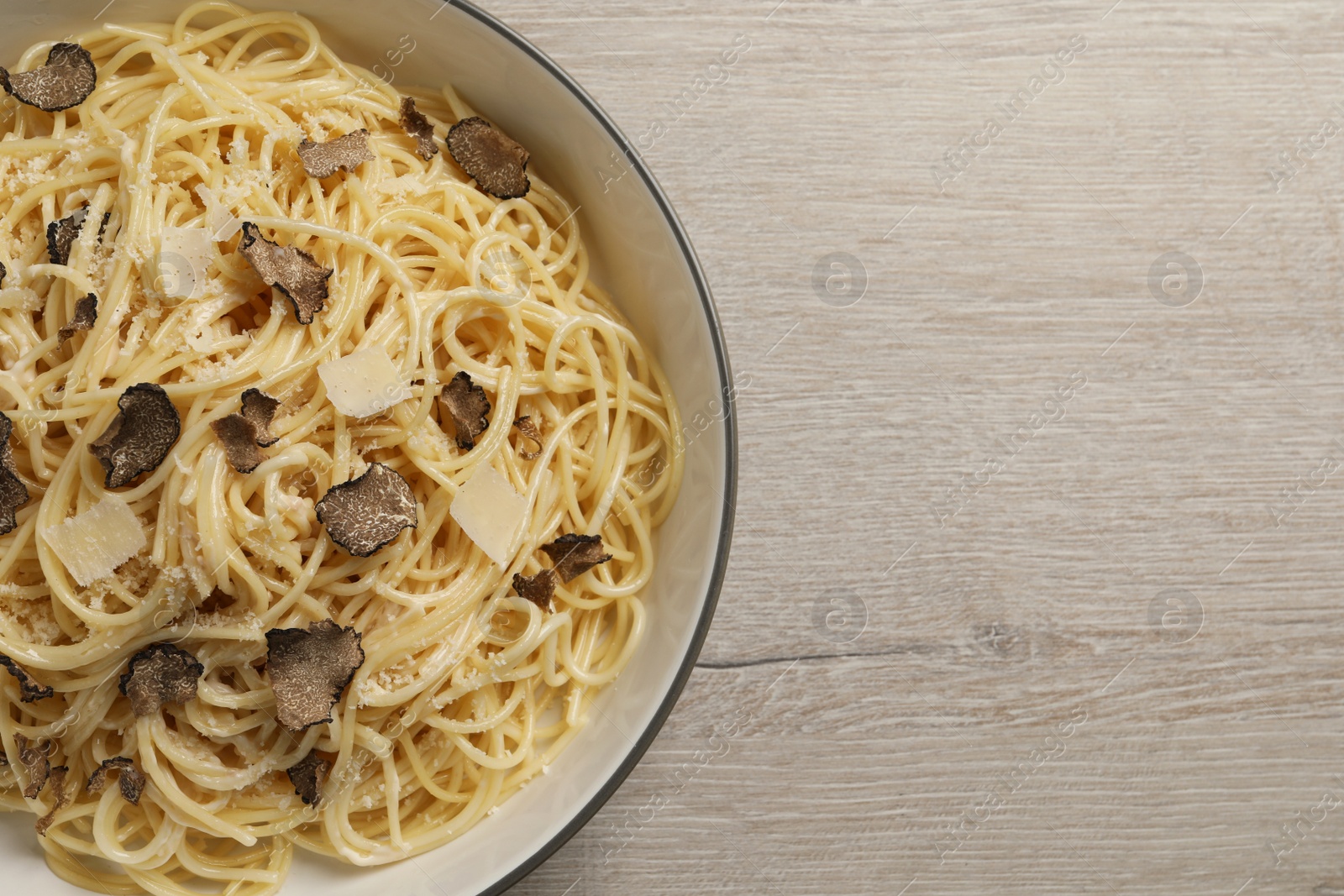 Photo of Tasty spaghetti with truffle on wooden table, top view. Space for text