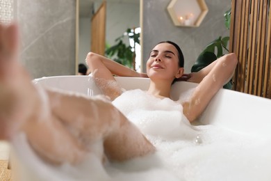 Photo of Beautiful young woman taking bubble bath at home