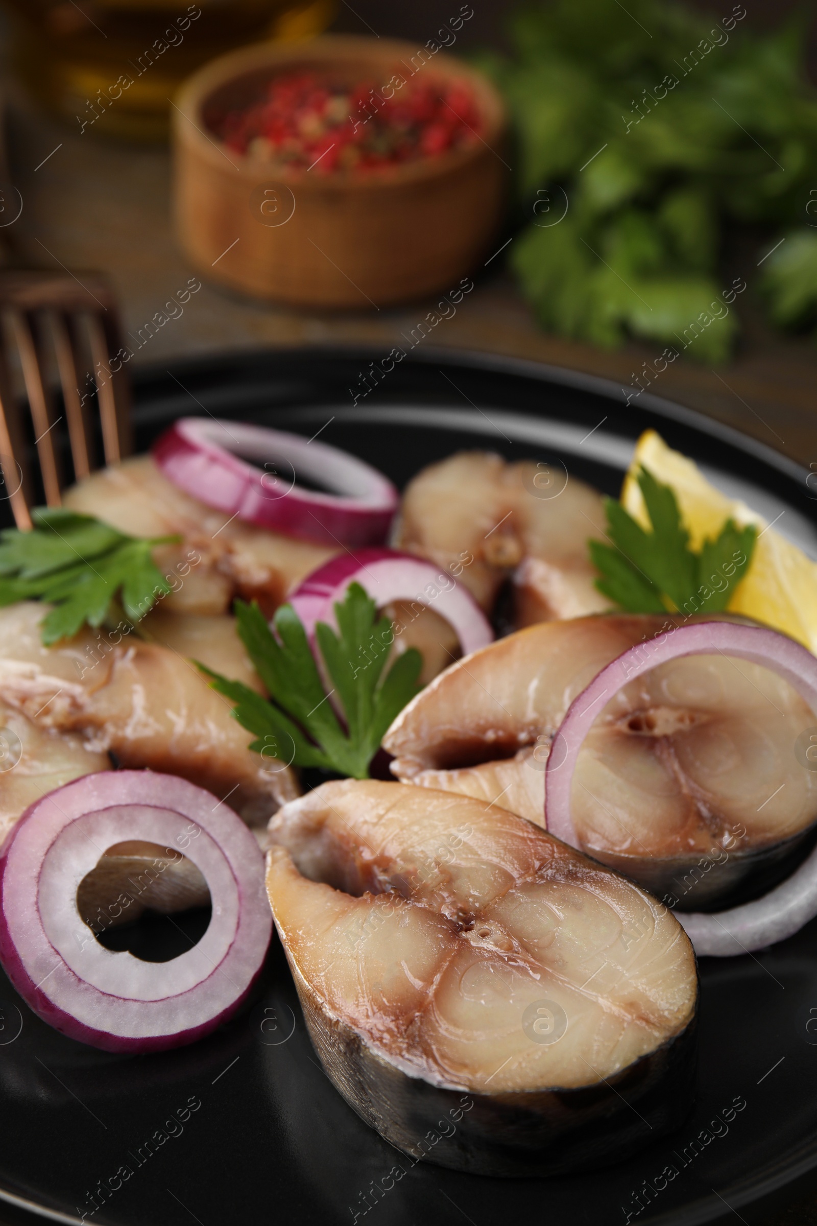 Photo of Slices of tasty salted mackerel, onion rings and parsley on table, closeup