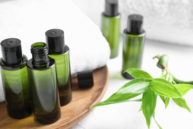 Composition with mini bottles of cosmetic products and towel on white table