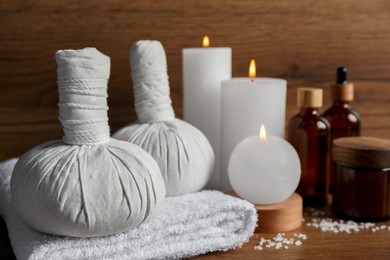 Beautiful spa composition with different care products and burning candles on wooden table, closeup. Space for text