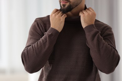Man in stylish sweater against blurred background, closeup