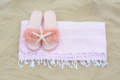 Photo of Blanket with stylish slippers and starfish on sand outdoors, top view. Beach accessories