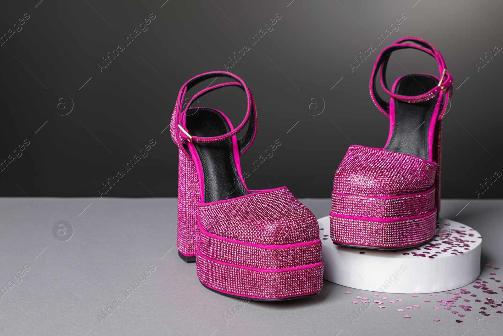 Photo of Fashionable punk square toe ankle strap pumps and confetti on light grey table, space for text. Shiny party platform high heeled shoes