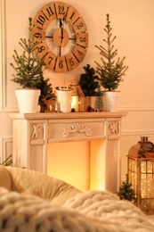 Photo of Beautiful room interior with decorative fireplace and potted fir trees. Christmas decor