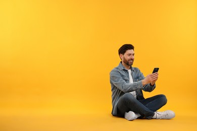 Photo of Happy man with smartphone on yellow background. Space for text