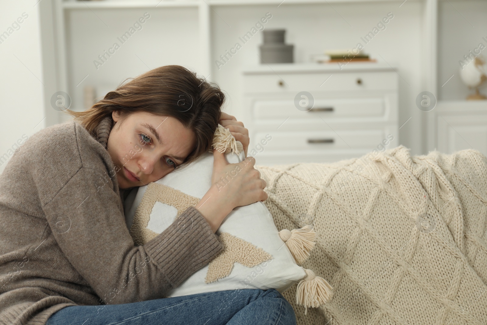 Photo of Sad young woman sitting on sofa at home, space for text