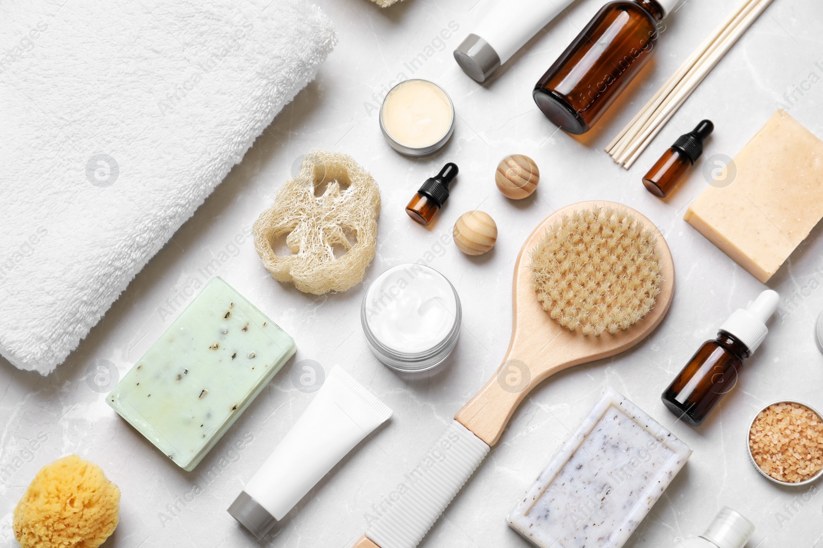 Photo of Flat lay composition with spa cosmetics and towel on light background