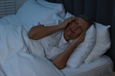 Woman suffering from headache in bed at night