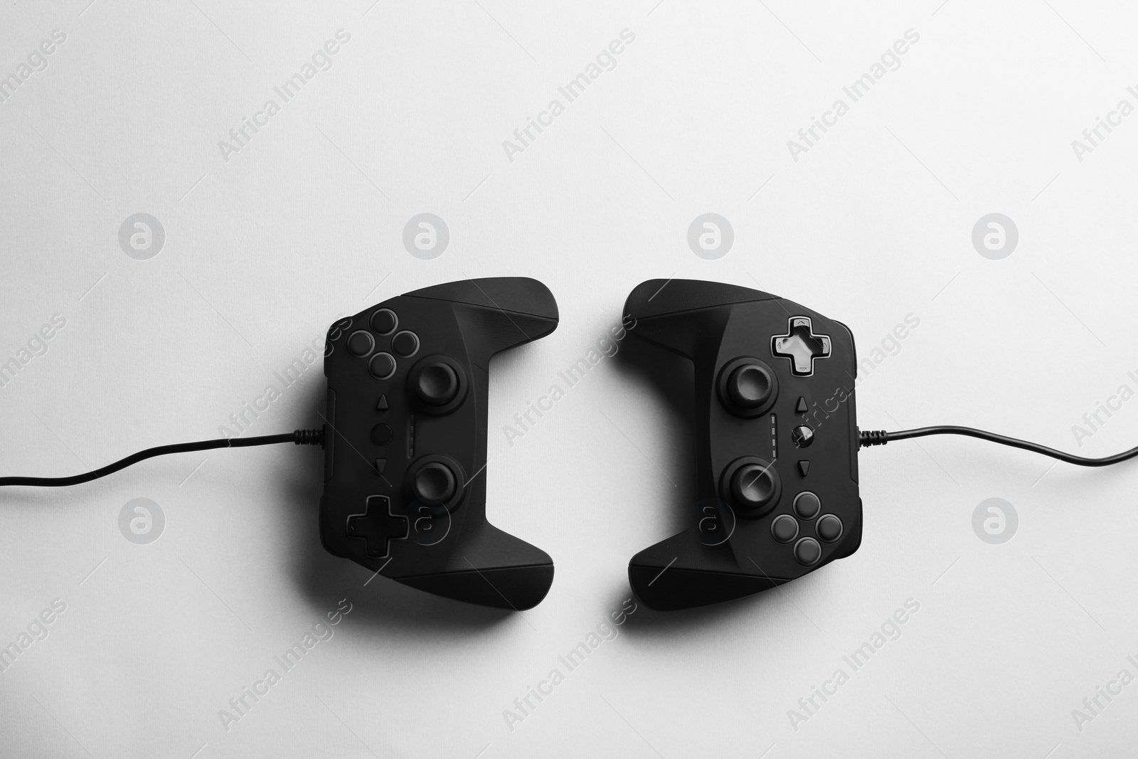 Photo of Modern video game controllers on light background, top view