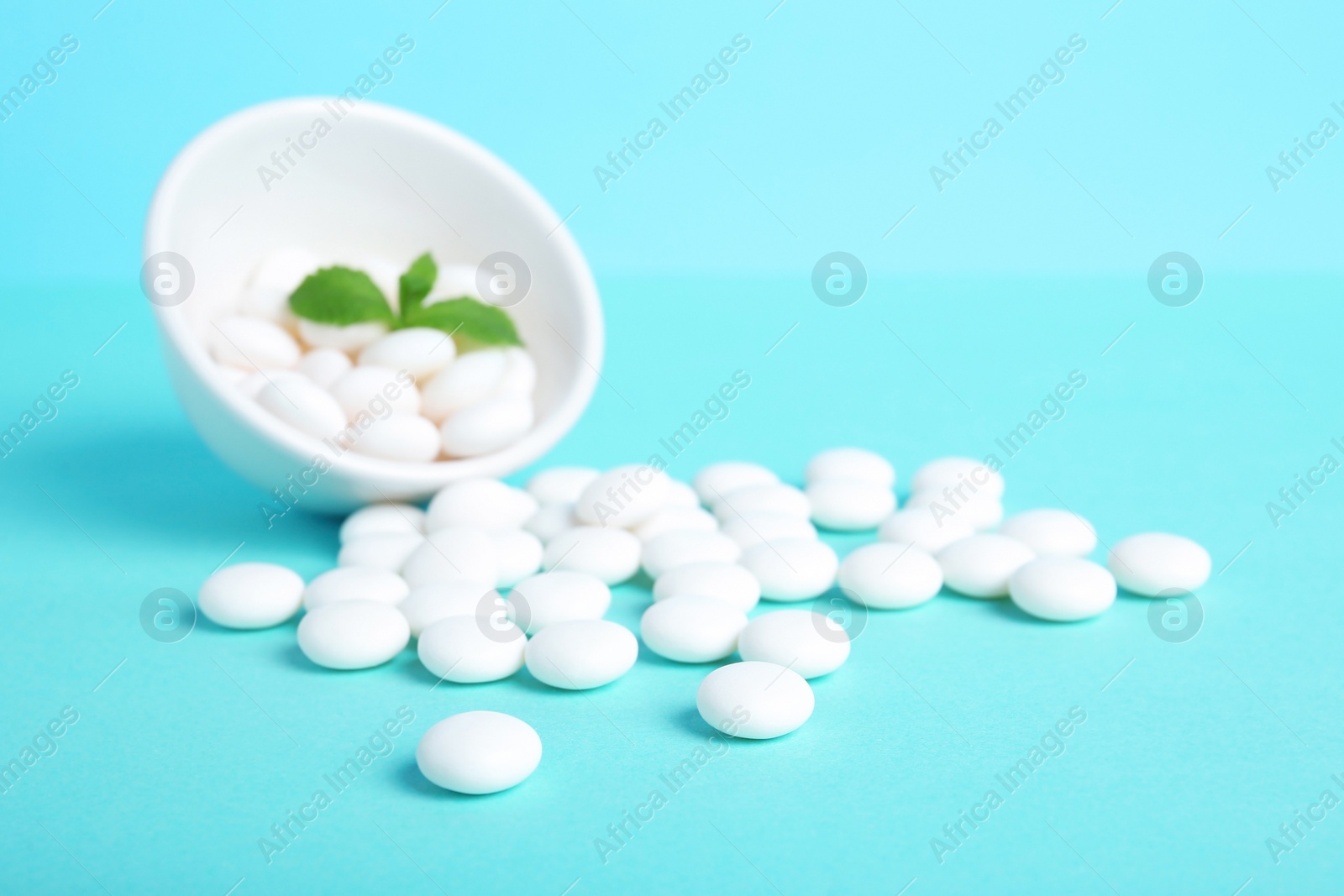 Photo of Bowl with tasty mint candies and leaves on color background