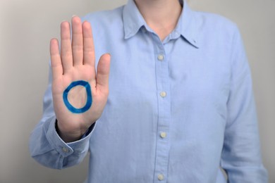 Woman showing blue circle drawn on palm against light grey background, closeup. World Diabetes Day