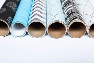 Photo of Rolls of festive wrapping paper and space for text on white background, closeup. Gift box packaging ideas