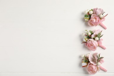 Photo of Beautiful boutonnieres on white background, flat lay. Space for text