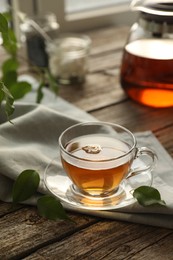 Photo of Tasty tea in cup on wooden table, closeup