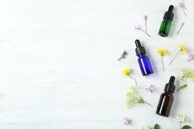 Photo of Flat lay composition with essential oils and flowers on white wooden table, space for text