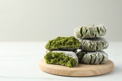 Photo of Board with stacked tasty matcha cookies on white table, closeup. Space for text