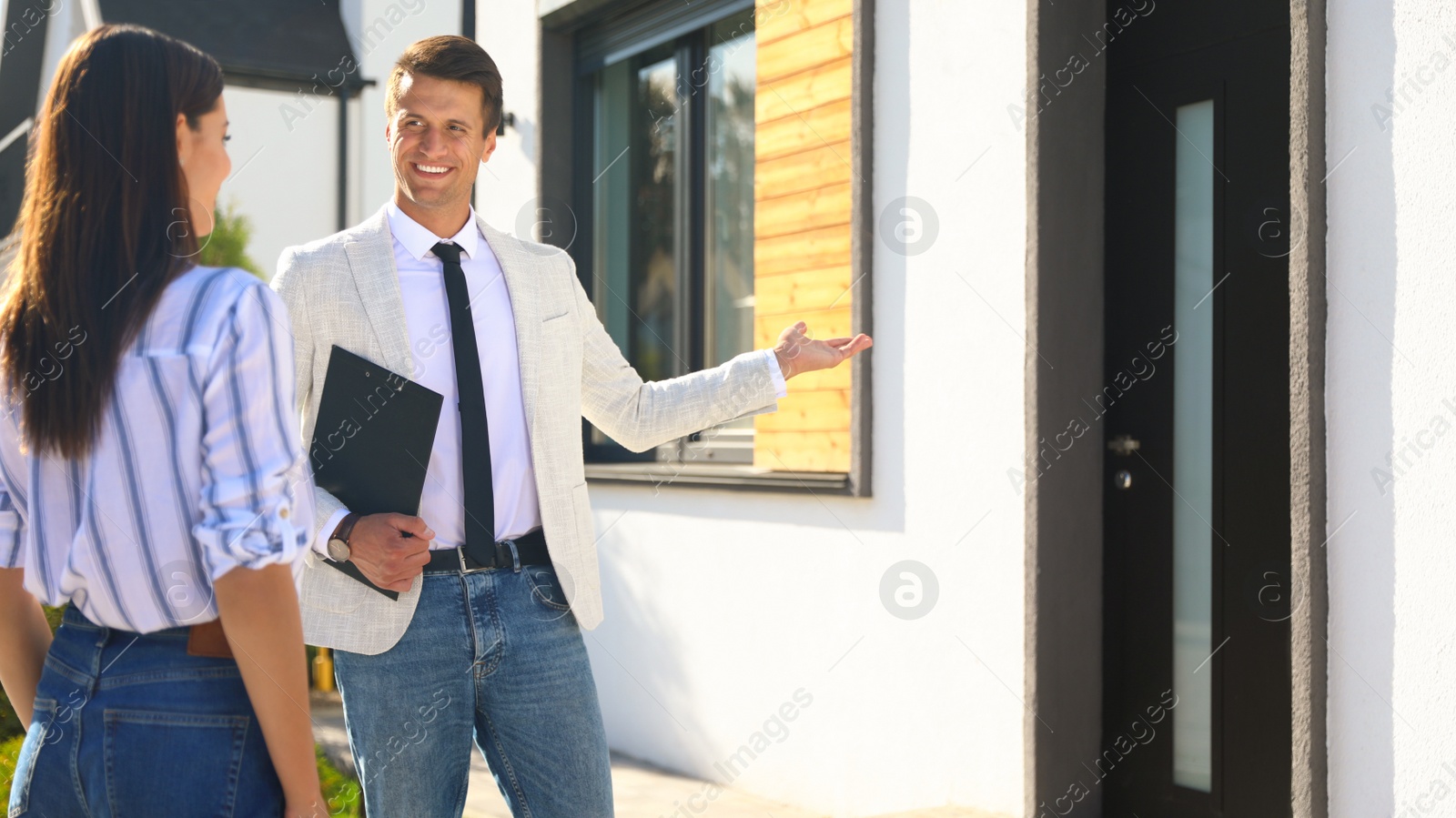 Photo of Real estate agent showing house to young woman outdoors