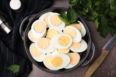 Photo of Fresh hard boiled eggs and parsley on brown table, flat lay
