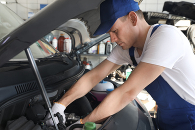 Professional auto mechanic fixing modern car in service center