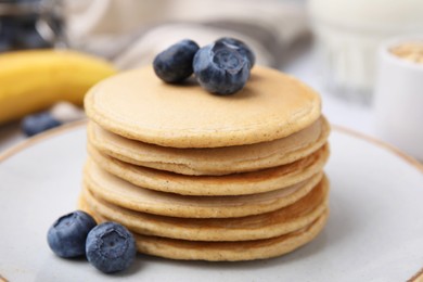 Photo of Tasty oatmeal pancakes with blueberries on plate, closeup