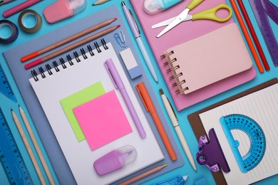 Photo of Flat lay composition with notebooks and other school stationery on light blue background. Back to school