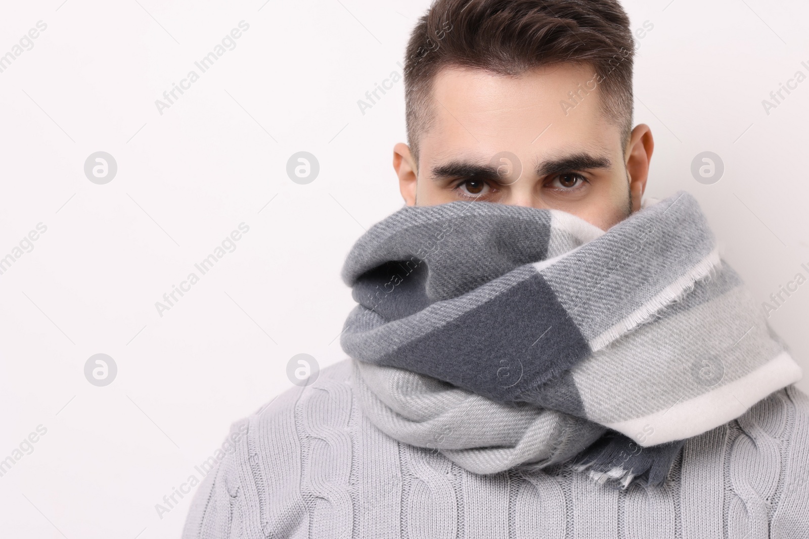 Photo of Man in warm scarf on light background. Space for text