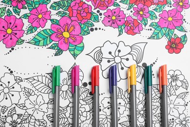 Photo of Felt tip pens on antistress coloring page, top view