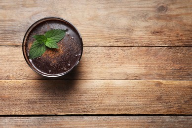 Glass of delicious hot chocolate and fresh mint on wooden table, top view. Space for text