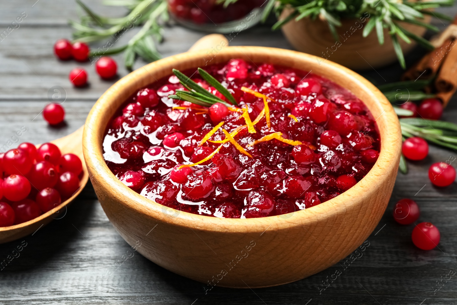 Photo of Fresh cranberry sauce with orange peel and rosemary on grey wooden table