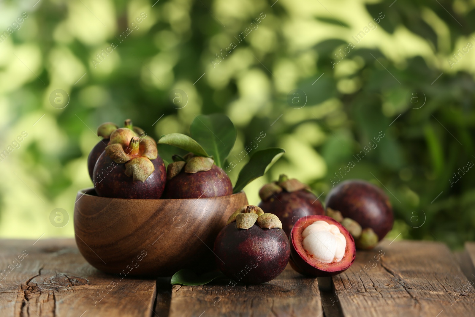 Photo of Delicious tropical mangosteen fruits on wooden table