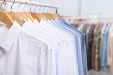 Photo of Dry-cleaning service. Many different clothes hanging on rack indoors, closeup