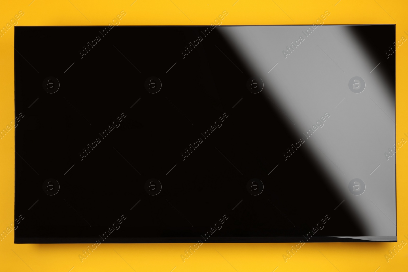 Photo of Modern TV with blank wide screen on orange background
