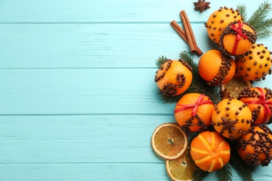 Flat lay composition with pomander balls made of fresh tangerines and cloves on light blue wooden table, space for text