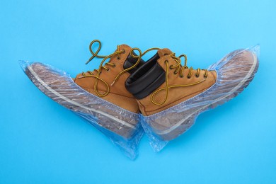 Men's boots in shoe covers on light blue background, top view