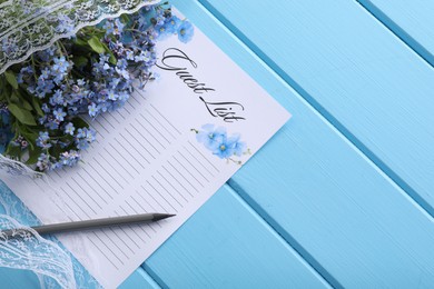 Guest list, pencil, lace ribbon and flowers on light blue wooden table, flat lay. Space for text