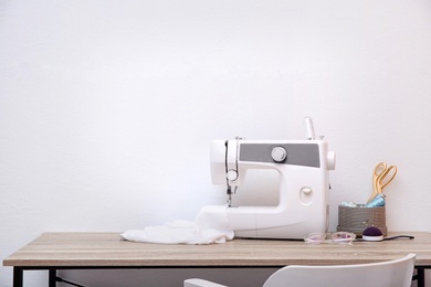 Photo of Sewing machine on table against light background