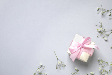 Photo of Flat lay composition with flowers and gift on light grey background, space for text. Happy Mother's day