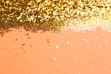 Photo of Shiny bright golden glitter on pale coral background. Space for text